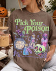 A woman wearing a t-shirt with a Halloween-themed graphic and holding a drink, with a pumpkin and other Halloween decorations visible in the background.