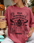 A woman wearing a red t-shirt with a Ouija board design and text printed on it, holding a drink in a glass.