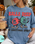 A woman wearing a blue t-shirt with a graphic design of two cartoon characters, one red and one green, holding a drink and standing in front of a pumpkin.