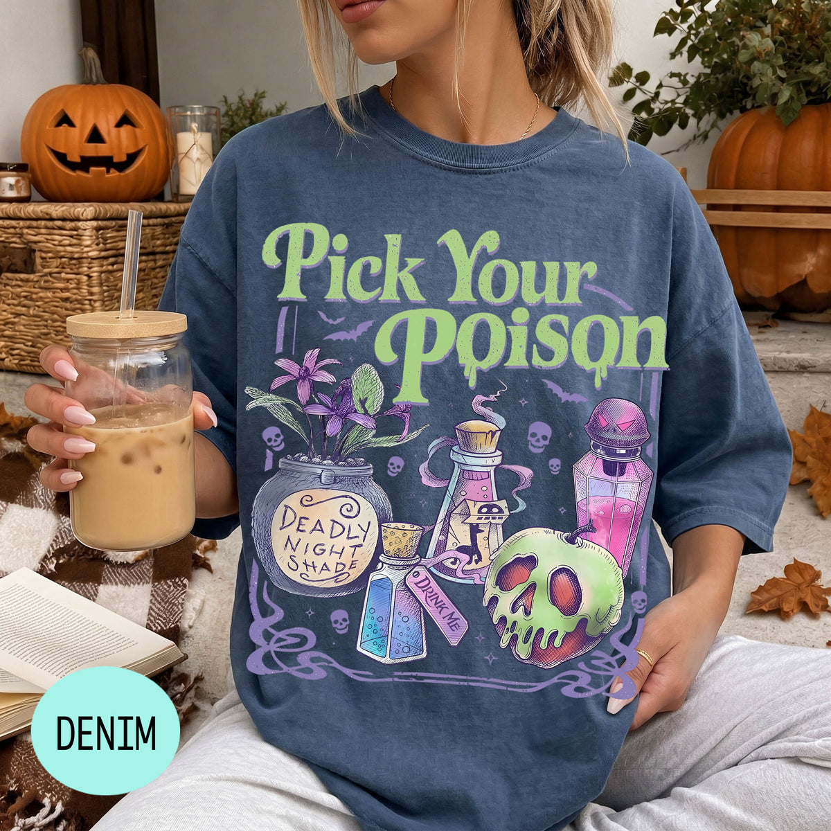A woman wearing a blue t-shirt with a Halloween-themed graphic and text, holding a drink in a glass.