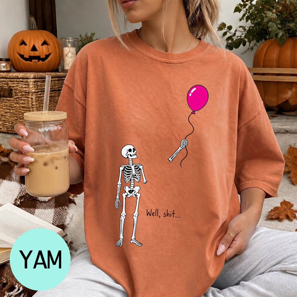 A woman wearing a t-shirt with a skeleton holding a balloon and the text "Well, shit..."
