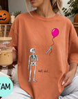 A woman wearing a t-shirt with a skeleton holding a balloon and the text "Well, shit..."