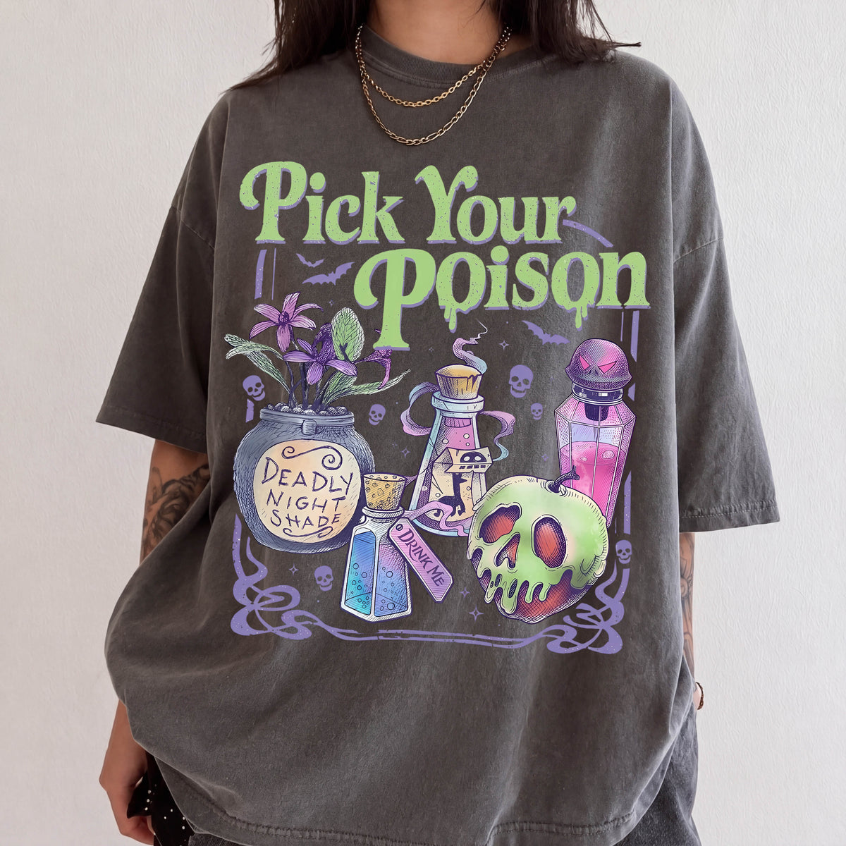 A person wearing a gray t-shirt with a graphic design featuring various Halloween-themed items such as a skull, a vase, and a bottle of poison.