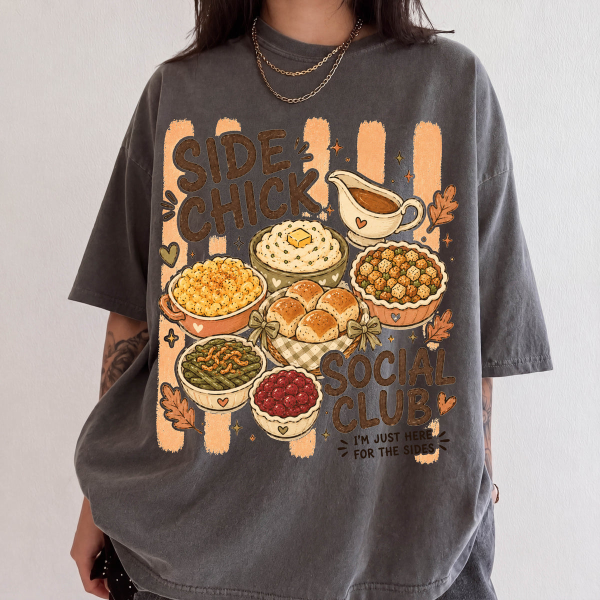 A person wearing a gray t-shirt with a graphic design depicting various Thanksgiving dishes and the text "SIDE CHICK SOCIAL CLUB" printed on it.