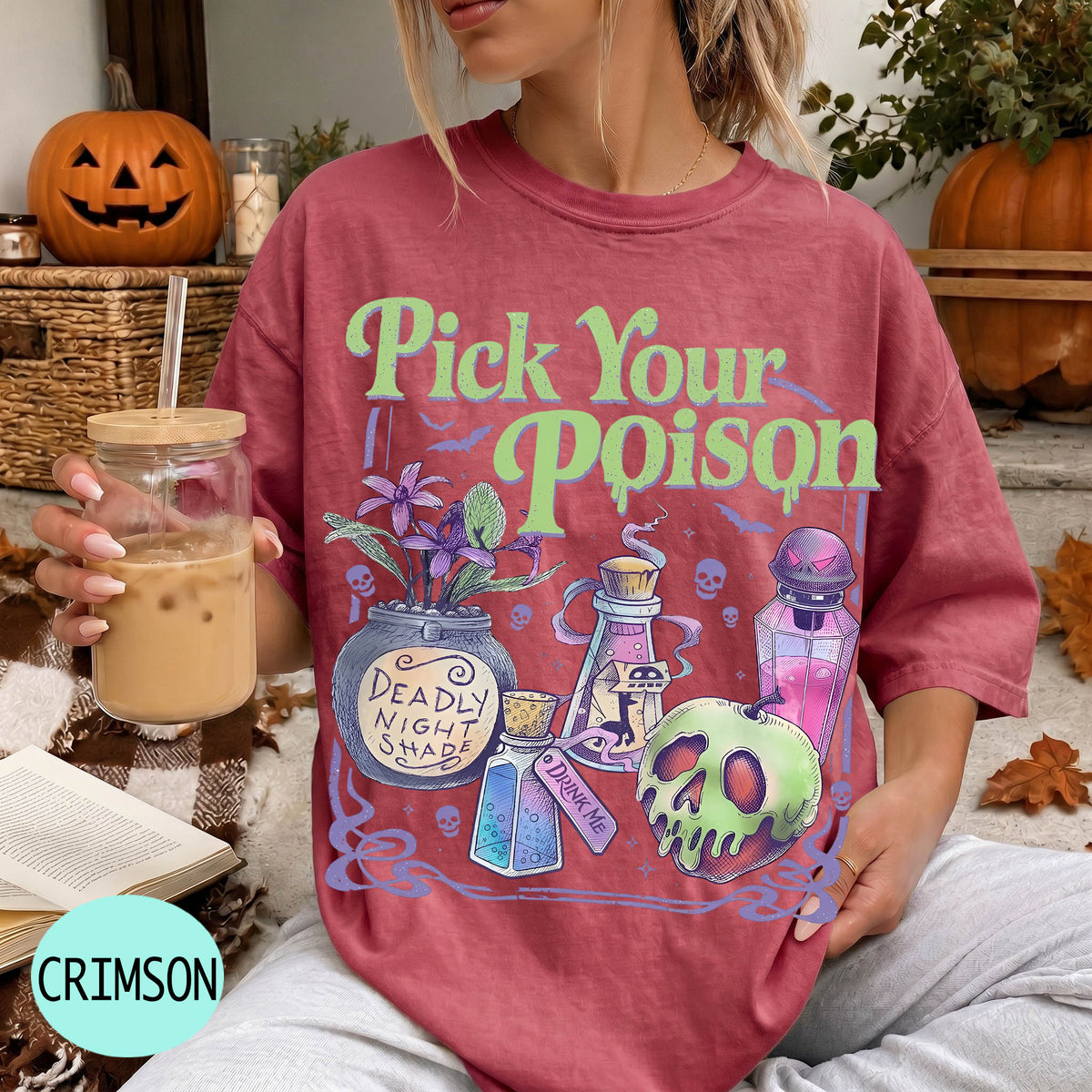 A woman wearing a red t-shirt with a Halloween-themed graphic and text, holding a drink in a glass.