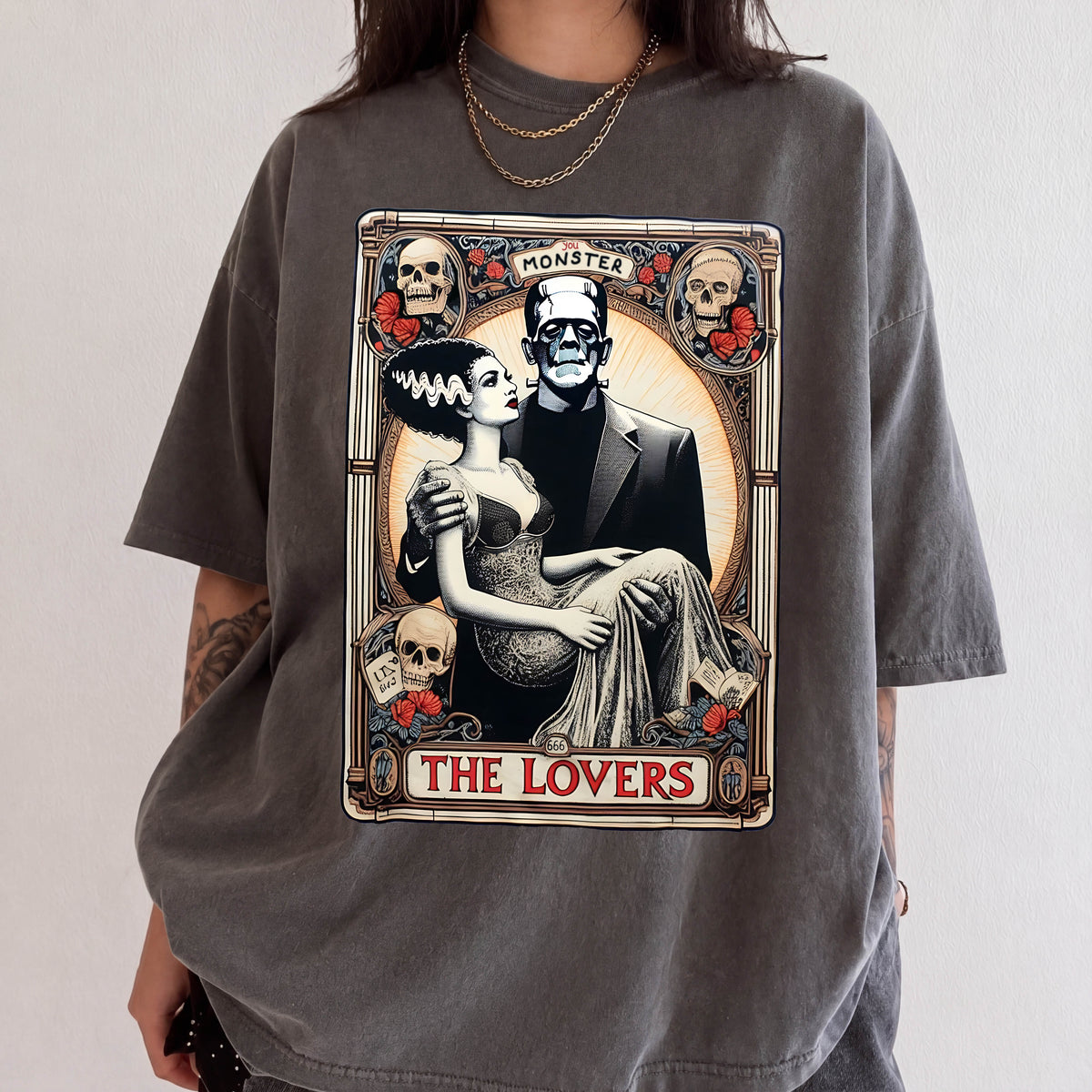 a graphic t-shirt with a design depicting a woman in a gown and a man in a suit, surrounded by various symbols and text, including the words "MONSTER", "THE LOVERS", and "THE LOVERS".