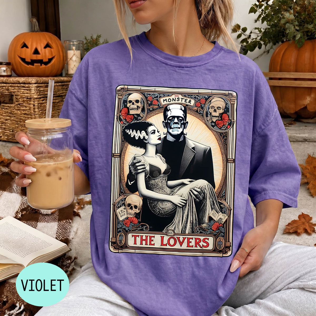 A woman wearing a purple t-shirt with a graphic design featuring a couple and the text "MONSTER THE LOVERS". She is holding a drink in her hand.