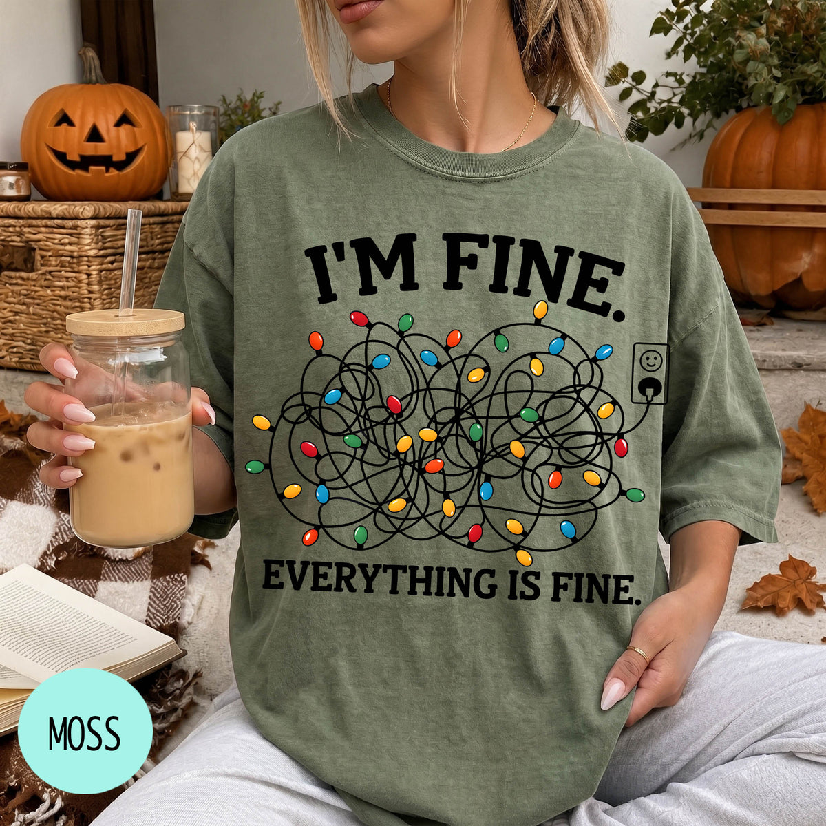 A person wearing a green t-shirt with a graphic design of colorful Christmas lights and the text "I'm Fine. EVERYTHING IS FINE."