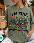 A person wearing a green t-shirt with a graphic design of colorful Christmas lights and the text "I'm Fine. EVERYTHING IS FINE."