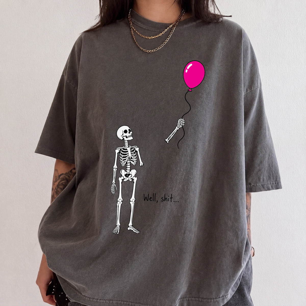A person wearing a gray t-shirt with a graphic design depicting a skeleton holding a pink balloon.