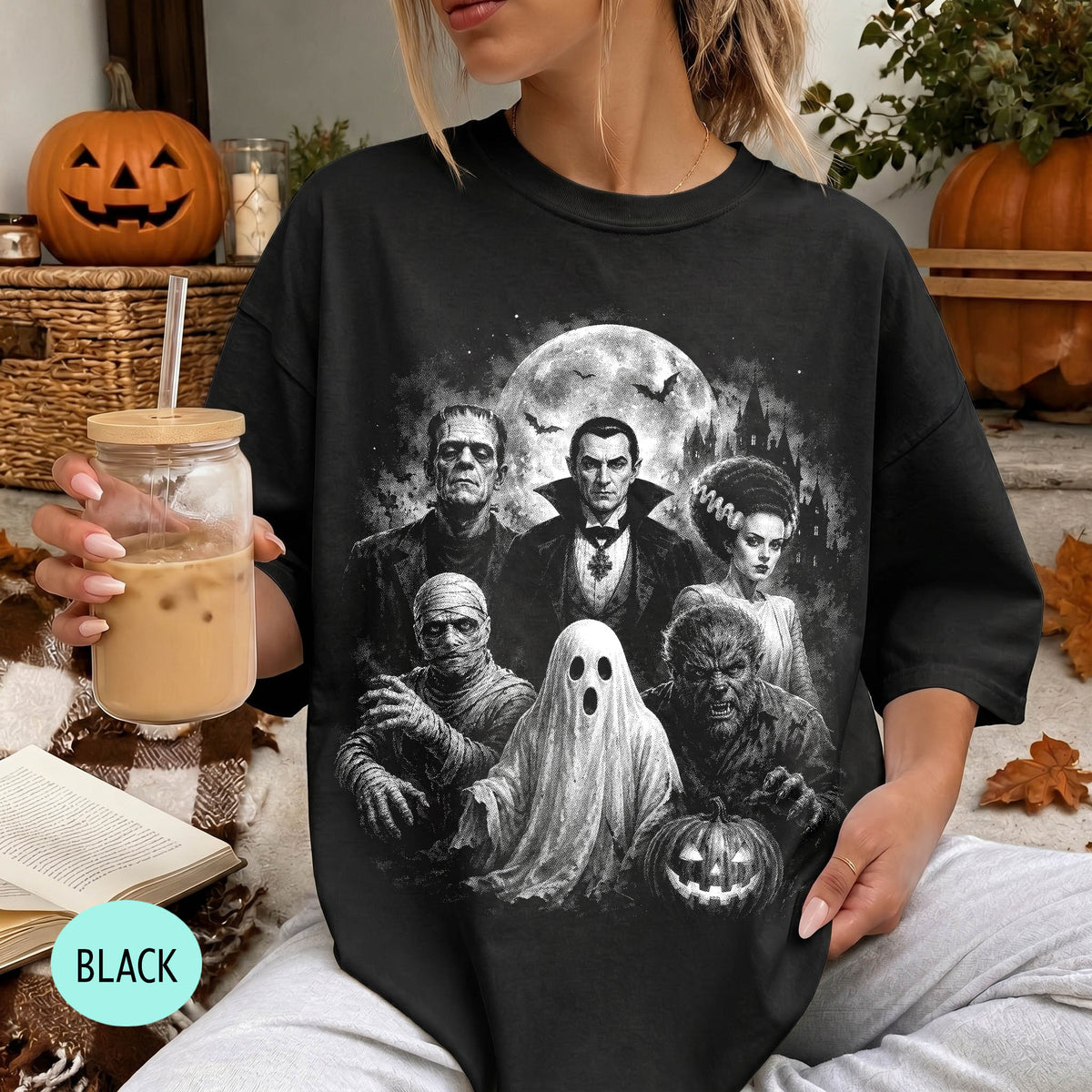 A woman wearing a black t-shirt with a graphic design featuring characters from the horror film "The Exorcist" and Halloween decorations.