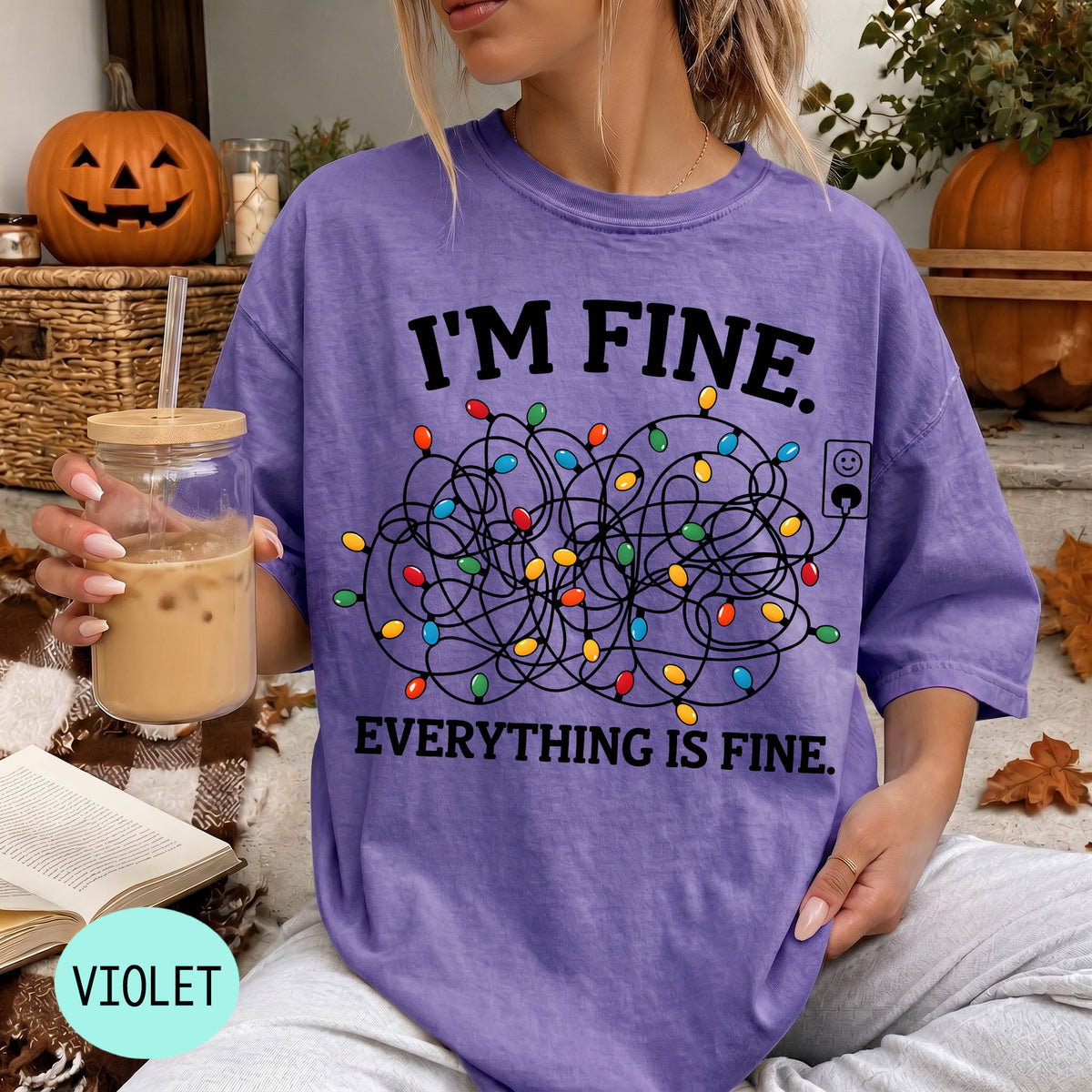 A person wearing a purple t-shirt with a graphic design of colorful Christmas lights and the text "I'm Fine. EVERYTHING IS FINE."