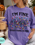 A person wearing a purple t-shirt with a graphic design of colorful Christmas lights and the text "I'm Fine. EVERYTHING IS FINE."