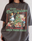 A person wearing a gray t-shirt with a Christmas-themed graphic design featuring a young girl decorating a Christmas tree and a boy holding a gift.