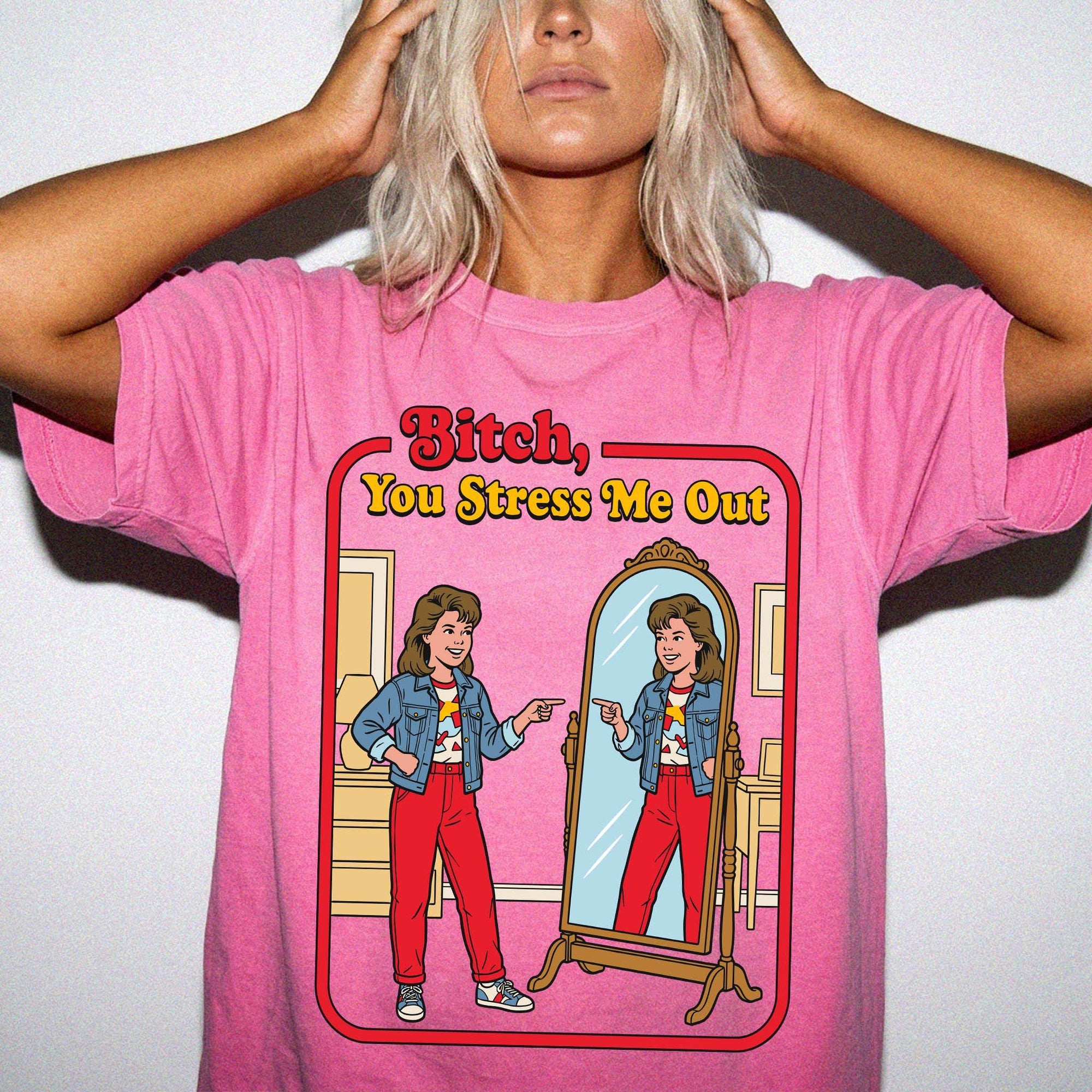 A woman wearing a pink t-shirt with a graphic design depicting a woman looking into a mirror and reading the text &amp;quot;Bitch, You Stress Me Out&amp;quot;.