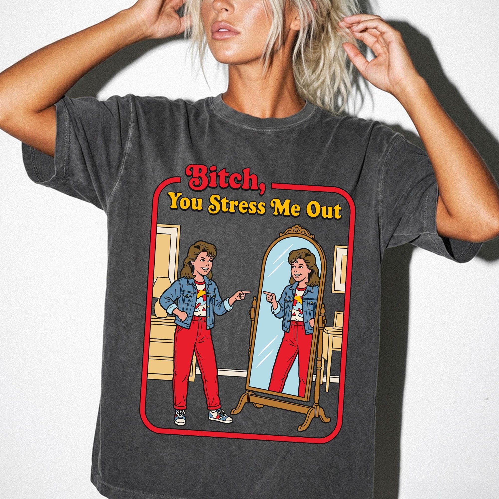 a woman wearing a gray t-shirt with a graphic design depicting a woman looking into a mirror and pointing at herself.