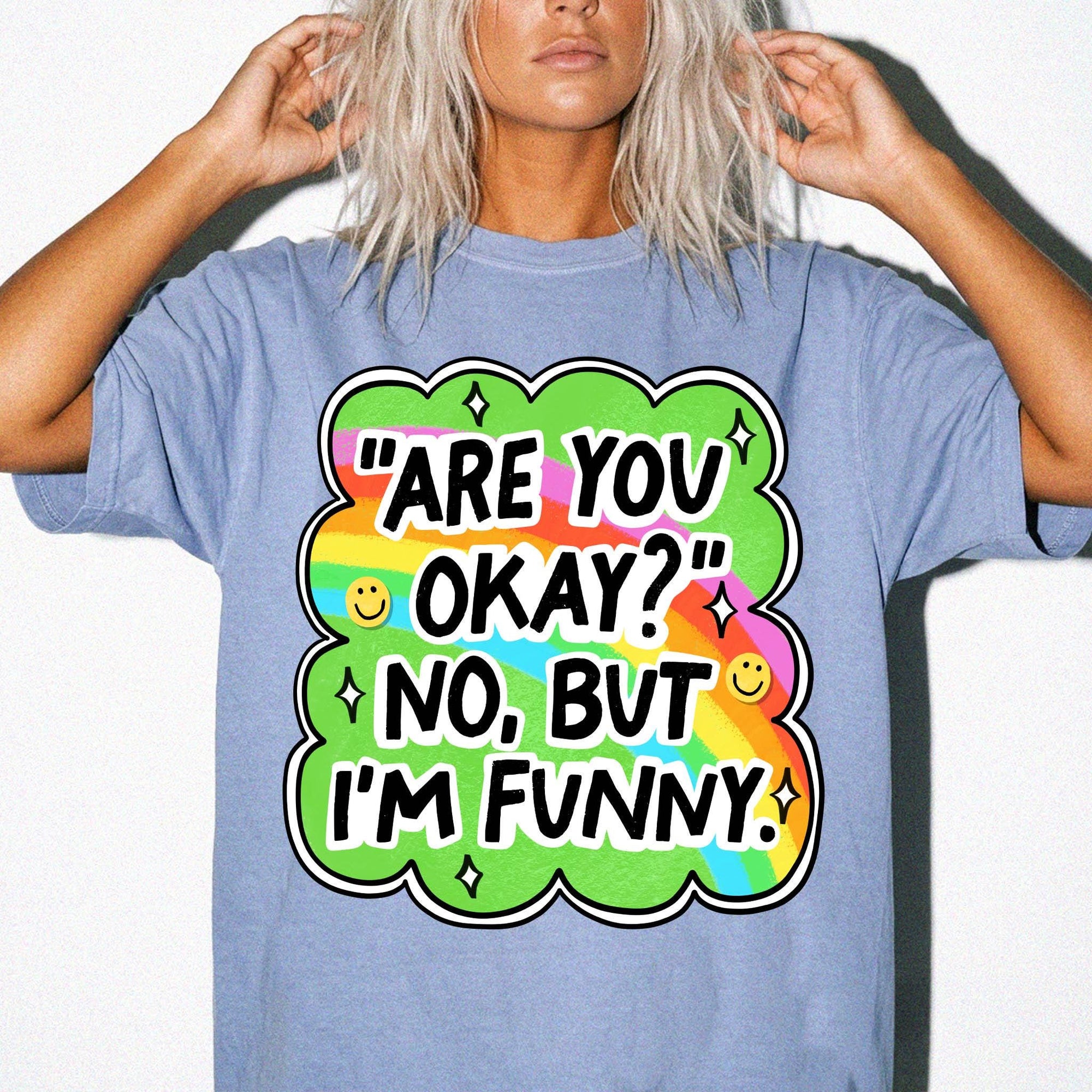 A person wearing a blue t-shirt with a colorful graphic and text that says "ARE YOU OKAY? NO, BUT I'M FUNNY."