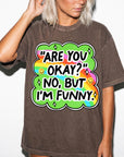 A woman wearing a brown t-shirt with a colorful graphic design and text.