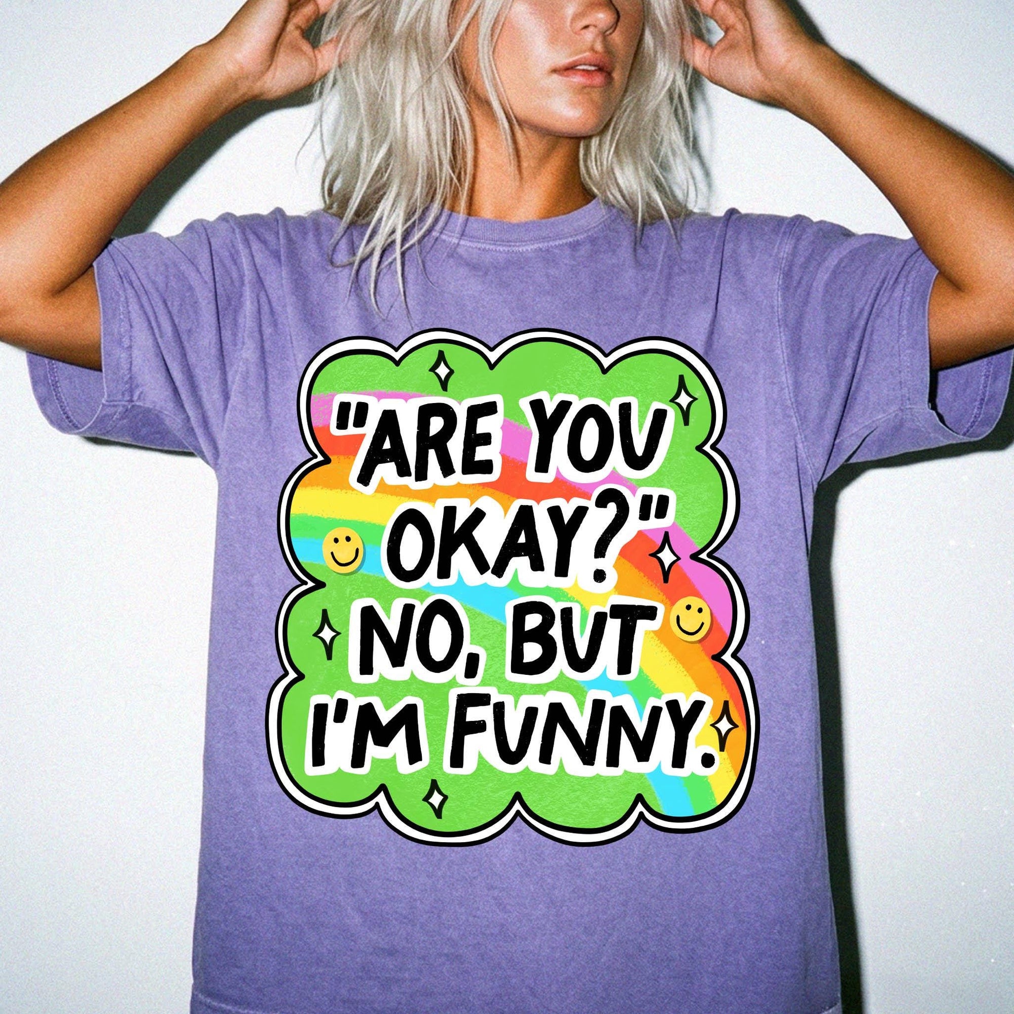 A person wearing a purple t-shirt with a colorful graphic and text that says &amp;quot;ARE YOU OKAY? NO, BUT I&amp;