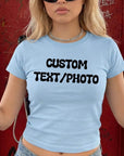 A woman wearing a light blue t-shirt with the text "CUSTOM TEXT/PHOTO" printed on it.