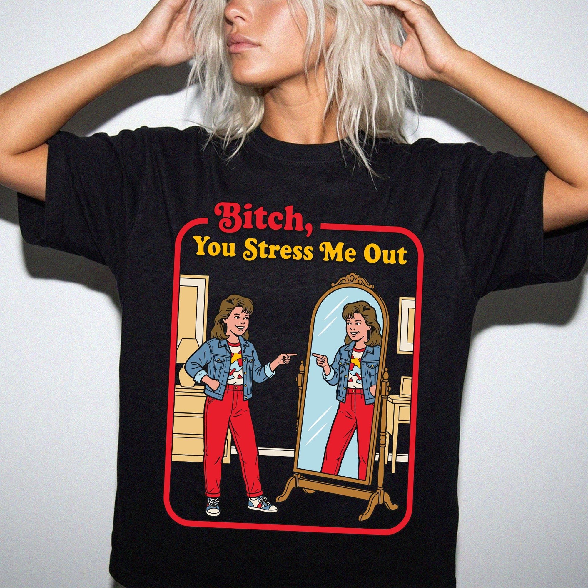 A woman wearing a black t-shirt with a graphic design depicting two women in a mirror, one of whom is pointing at the other.