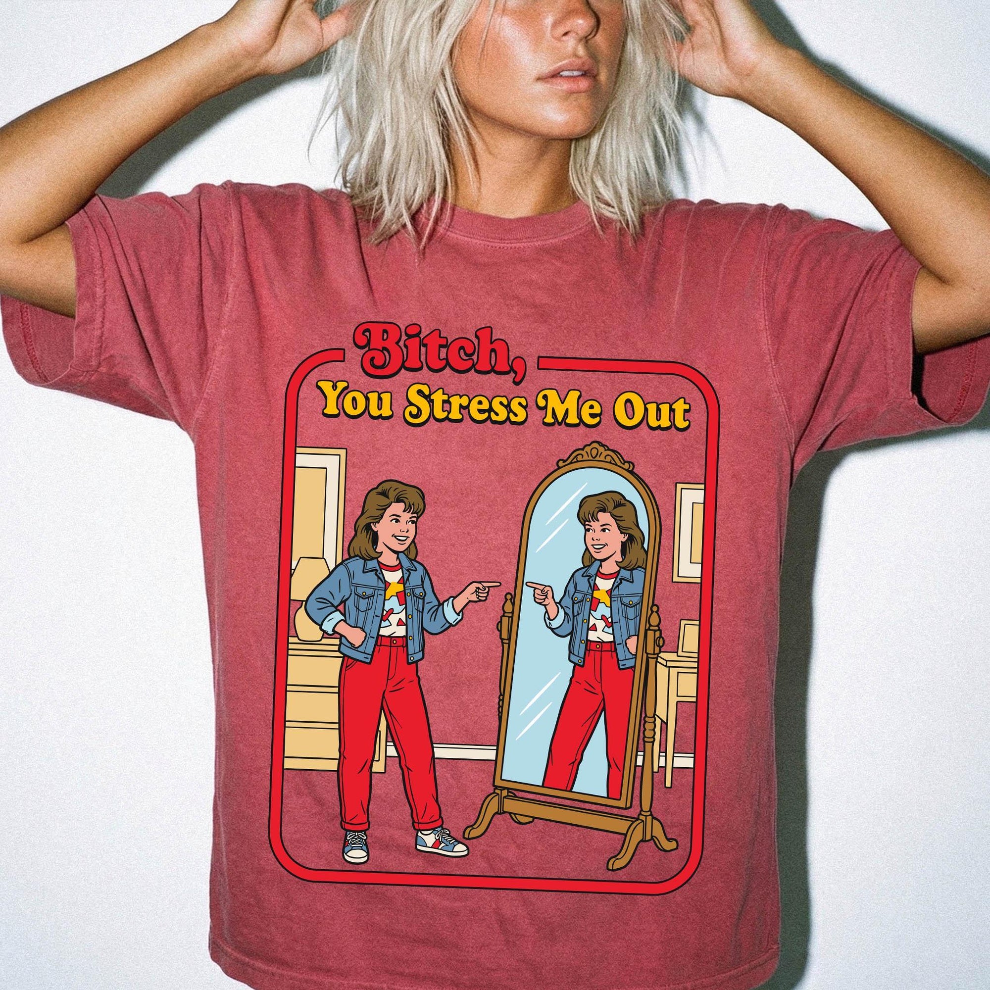 A woman wearing a red t-shirt with a graphic design depicting a woman looking into a mirror and being berated by a character.