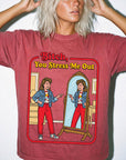 A woman wearing a red t-shirt with a graphic design depicting a woman looking into a mirror and being berated by a character.