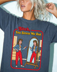 A woman with blonde hair wearing a blue t-shirt with a graphic design depicting a woman looking into a mirror and pointing at herself.