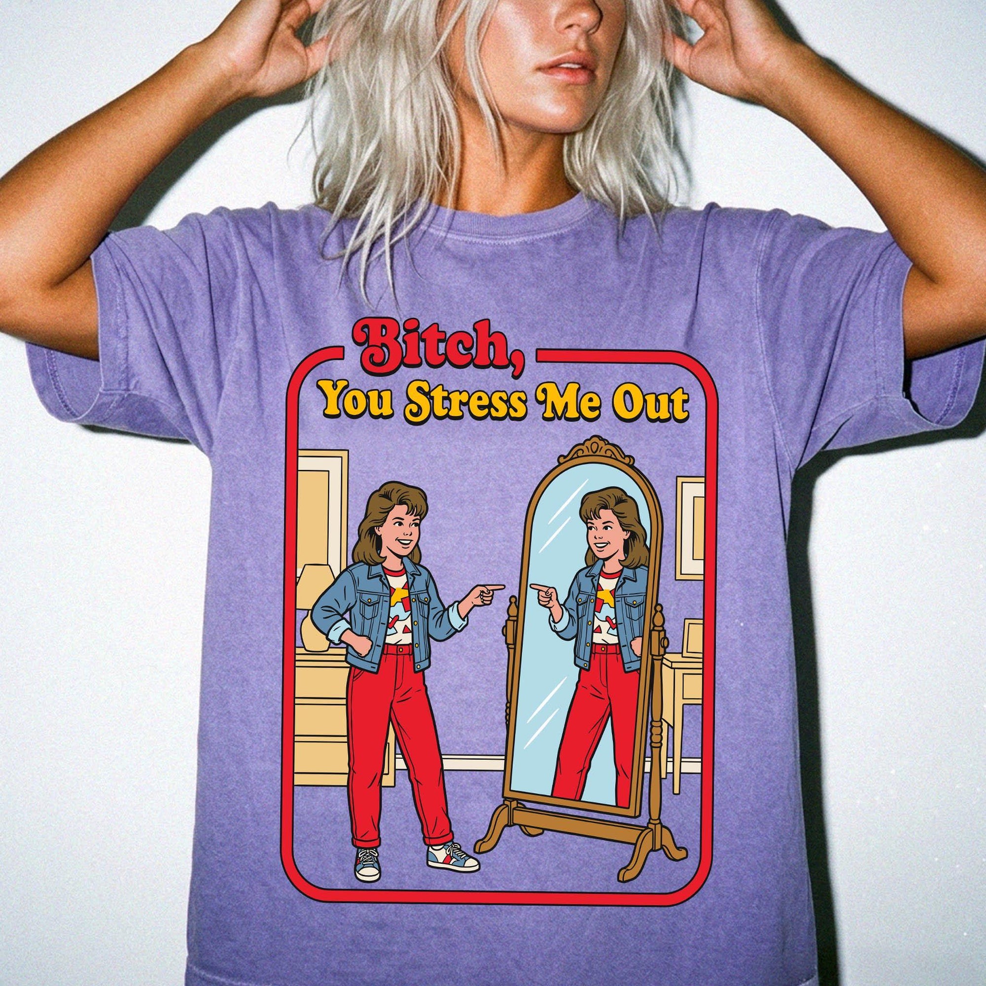a woman wearing a purple t-shirt with a graphic design depicting a woman looking into a mirror and pointing at herself.