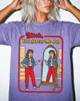 a woman wearing a purple t-shirt with a graphic design depicting a woman looking into a mirror and pointing at herself.