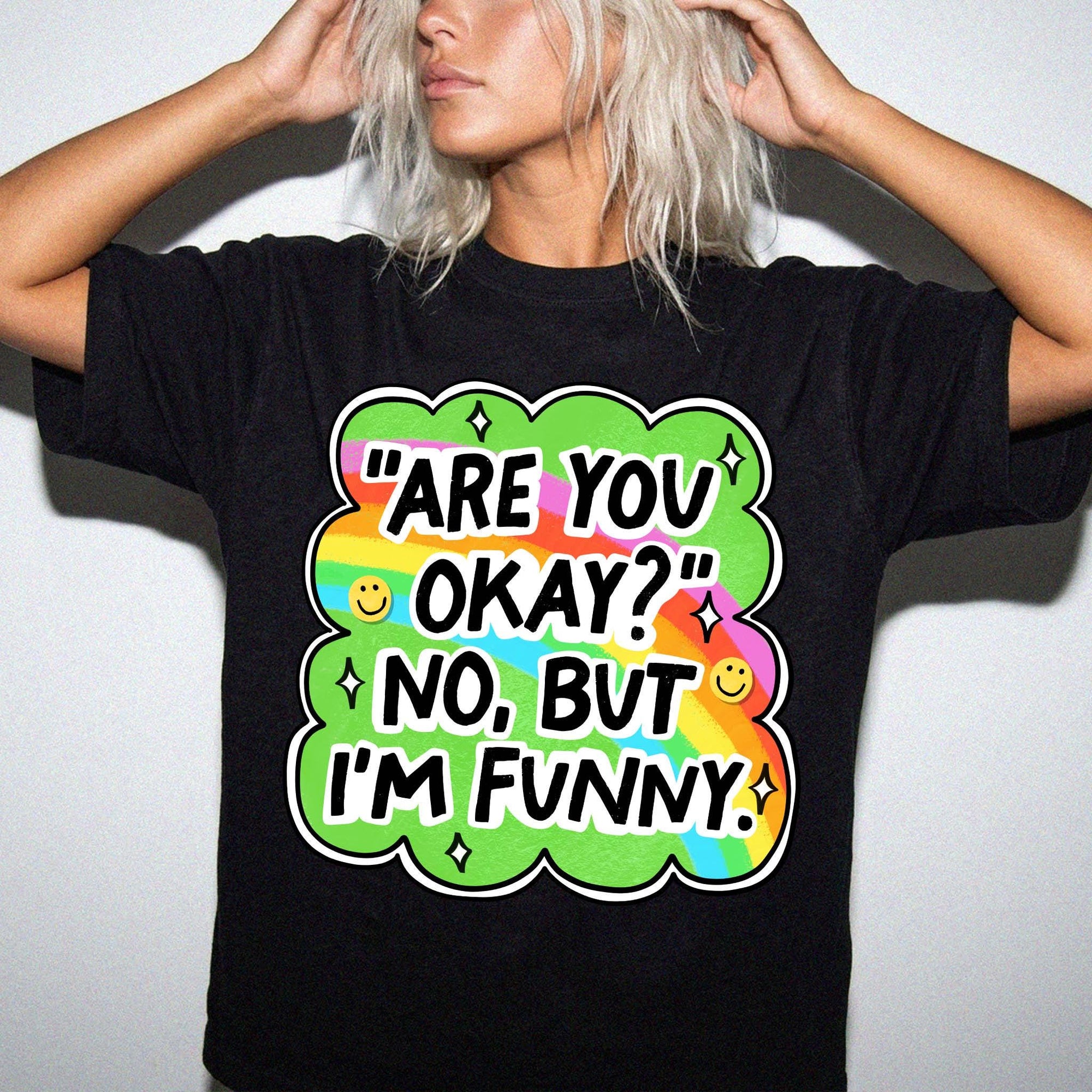 A person wearing a black t-shirt with a colorful graphic design and text that says "ARE YOU OKAY? NO, BUT I'M FUNNY?"