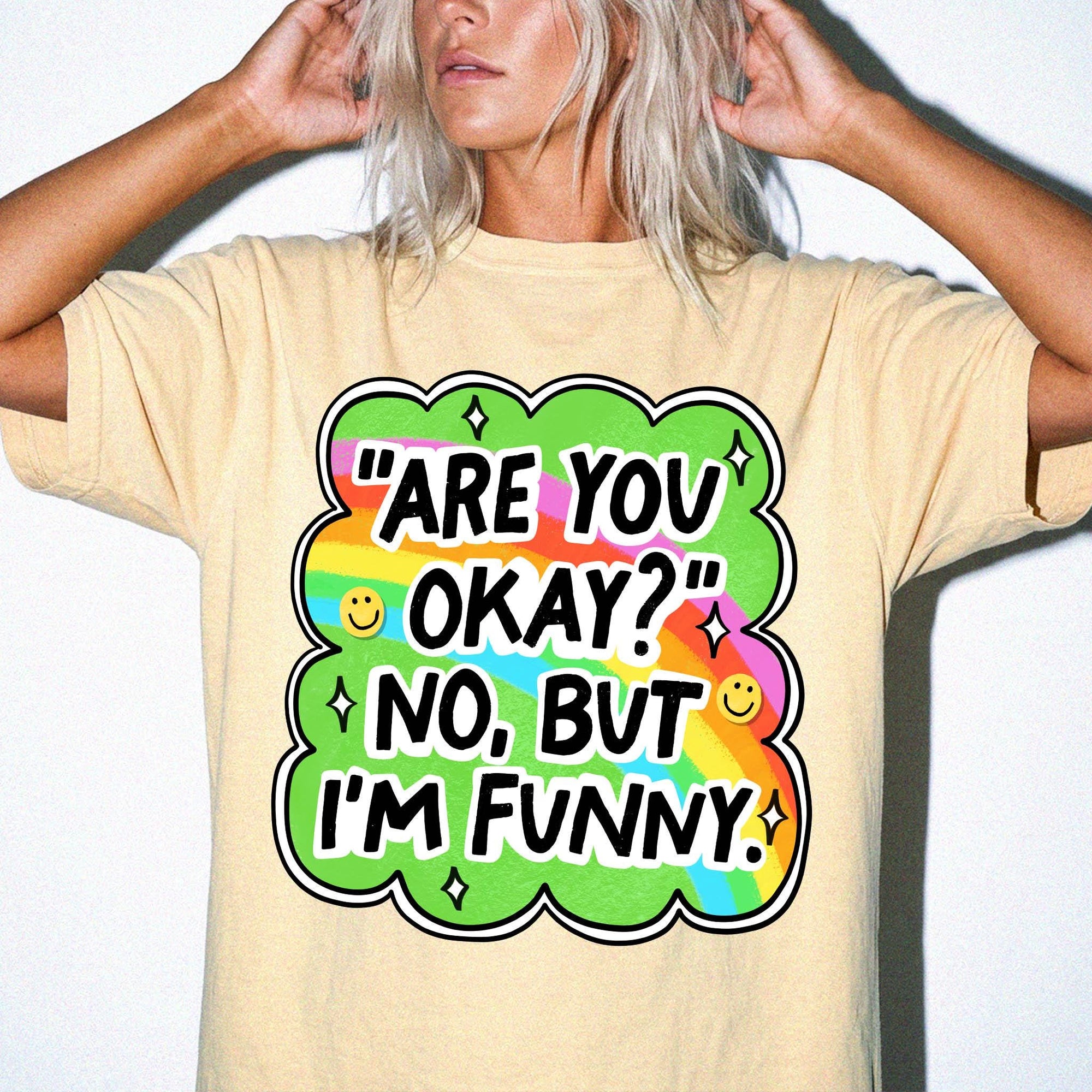 A person wearing a yellow t-shirt with a colorful graphic and text that says "ARE YOU OKAY? NO, BUT I'M FUNNY".