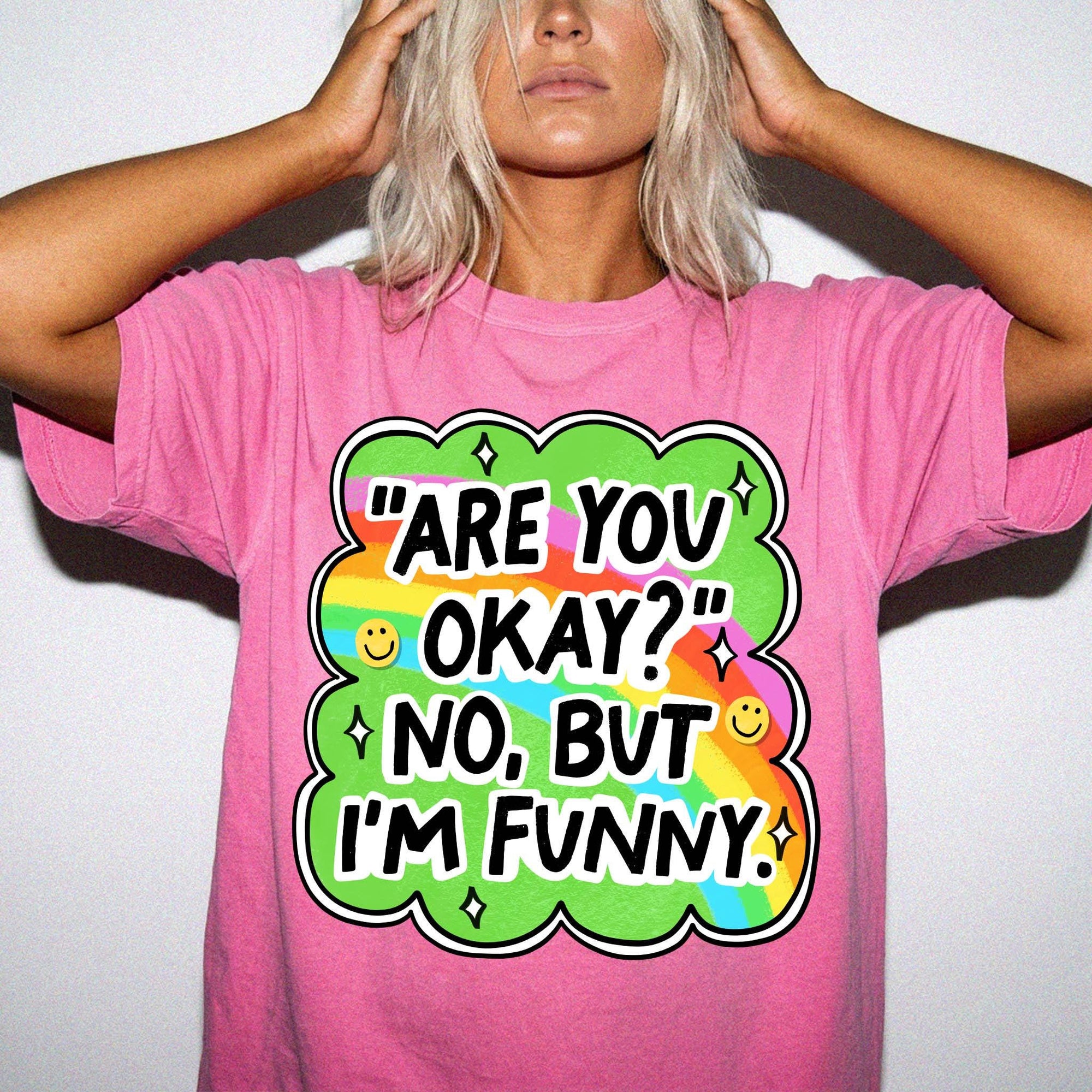 A woman wearing a pink t-shirt with a colorful graphic and text on it.
