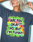 A woman wearing a gray t-shirt with a colorful graphic design and text on it.