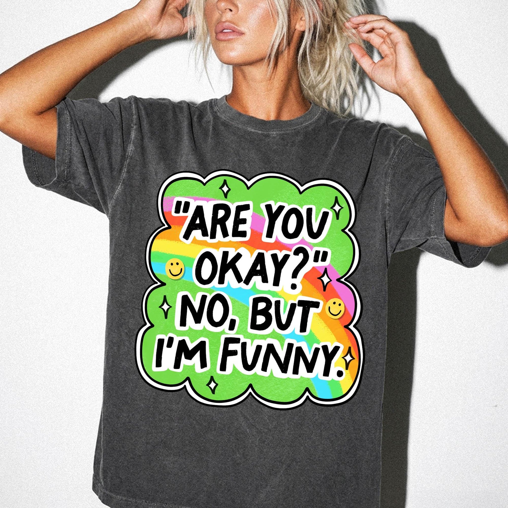 A woman wearing a gray t-shirt with a colorful graphic and text that says &amp;quot;ARE YOU OKAY? NO, BUT I&amp;