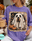 A woman wearing a purple t-shirt with a graphic of a ghost dog holding a pumpkin and a glass of iced coffee.