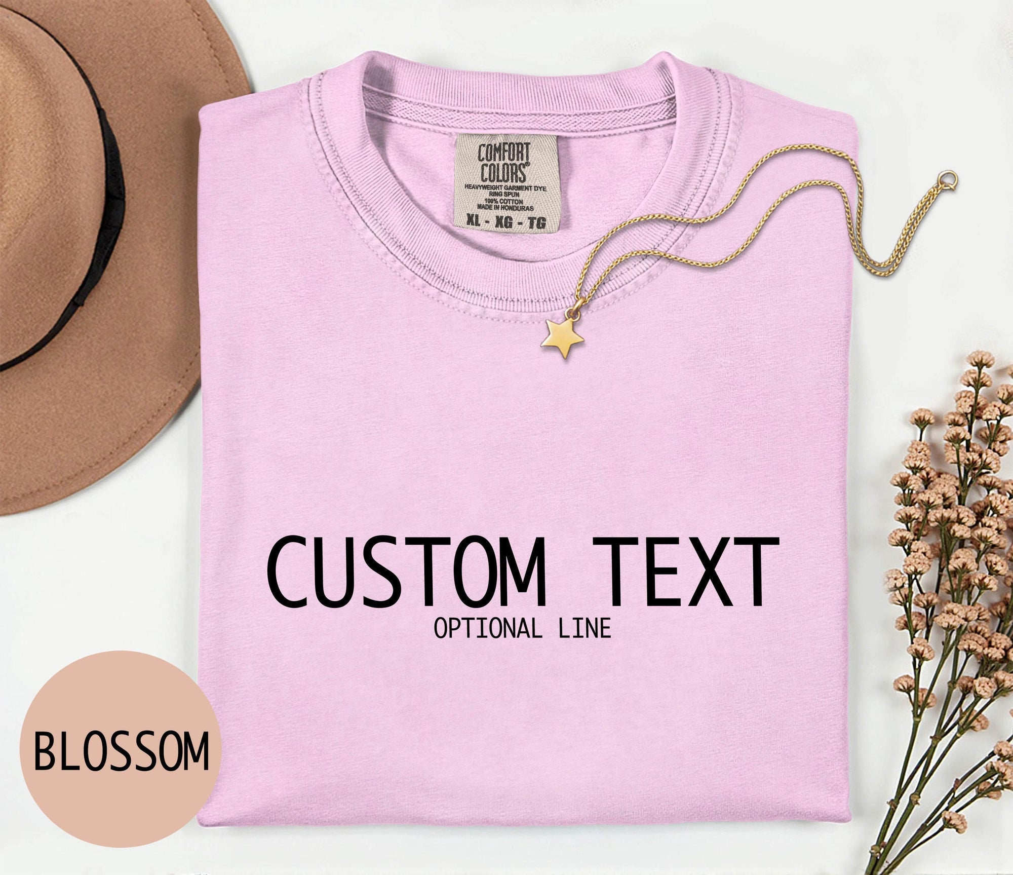 a pink t-shirt with the text &amp;quot;CUSTOM TEXT&amp;quot; and &amp;quot;OPTIONAL LINE&amp;quot; printed on it, along with a necklace and a hat.