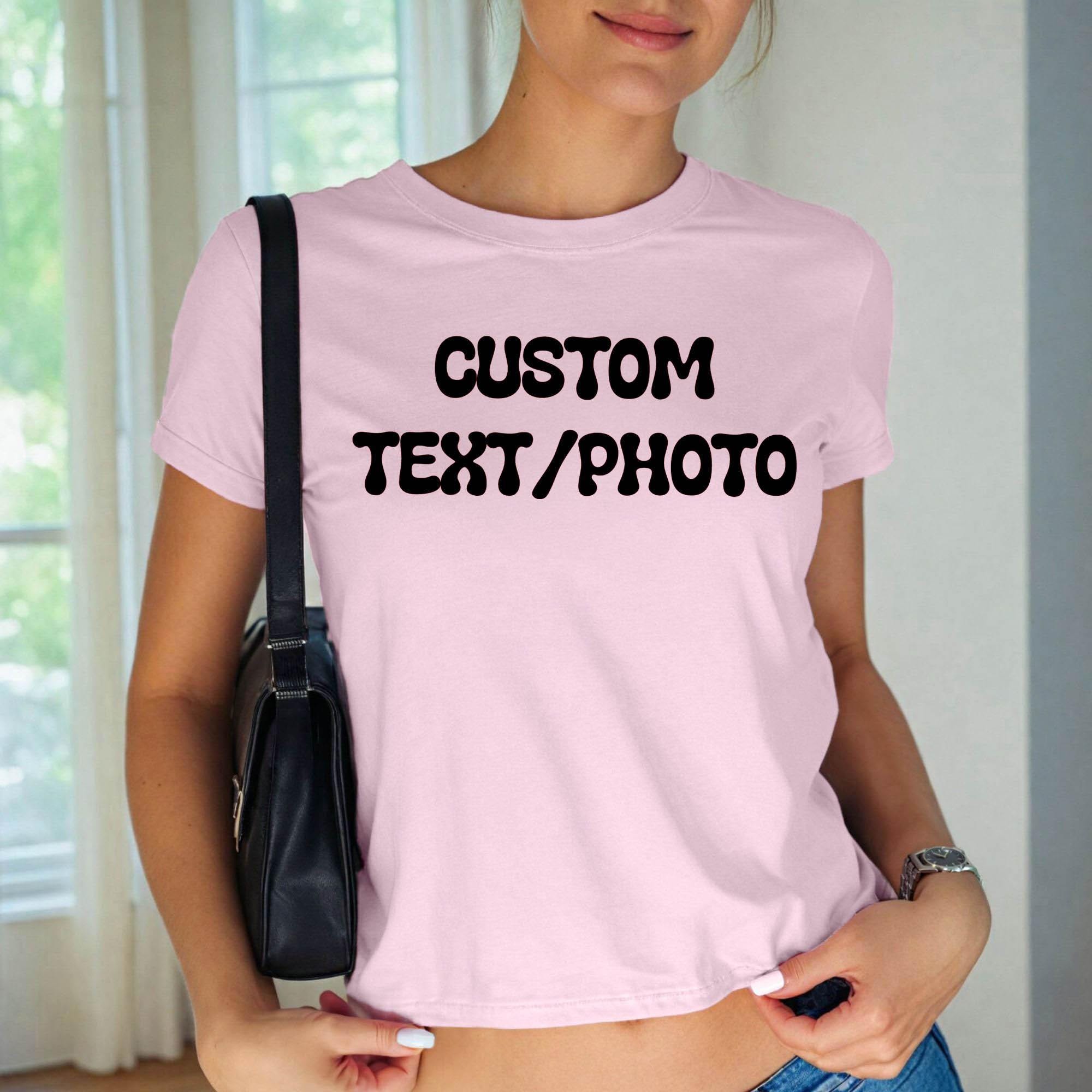 A woman wearing a pink t-shirt with the text &amp;quot;CUSTOM TEXT/PHOTO&amp;quot; printed on it, standing in front of a window.