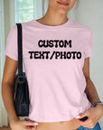 A woman wearing a pink t-shirt with the text "CUSTOM TEXT/PHOTO" printed on it, standing in front of a window.