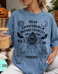 A woman wearing a blue t-shirt with a Ouija board design and text printed on it, holding a drink in a glass.