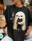 A woman wearing a black t-shirt with a graphic of a ghost holding a coffee mug and a black cat.
